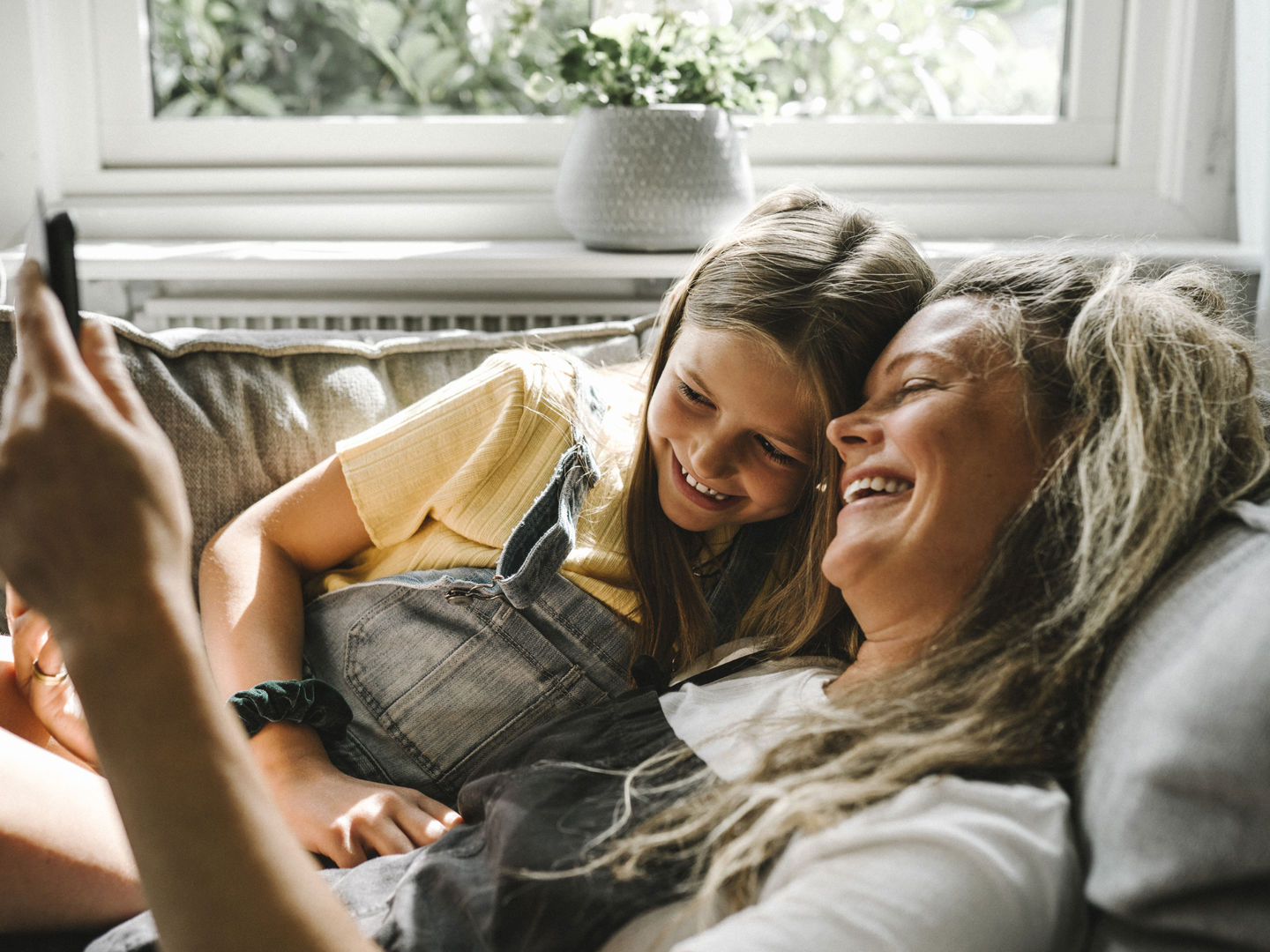 A mother and daughter on the sofa looking at a phone