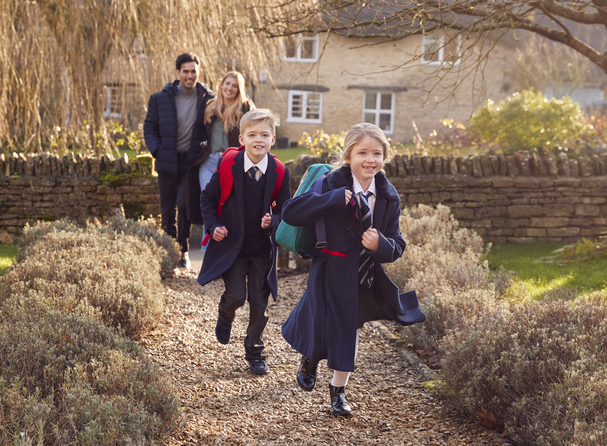 Children running up garden path with parents behind