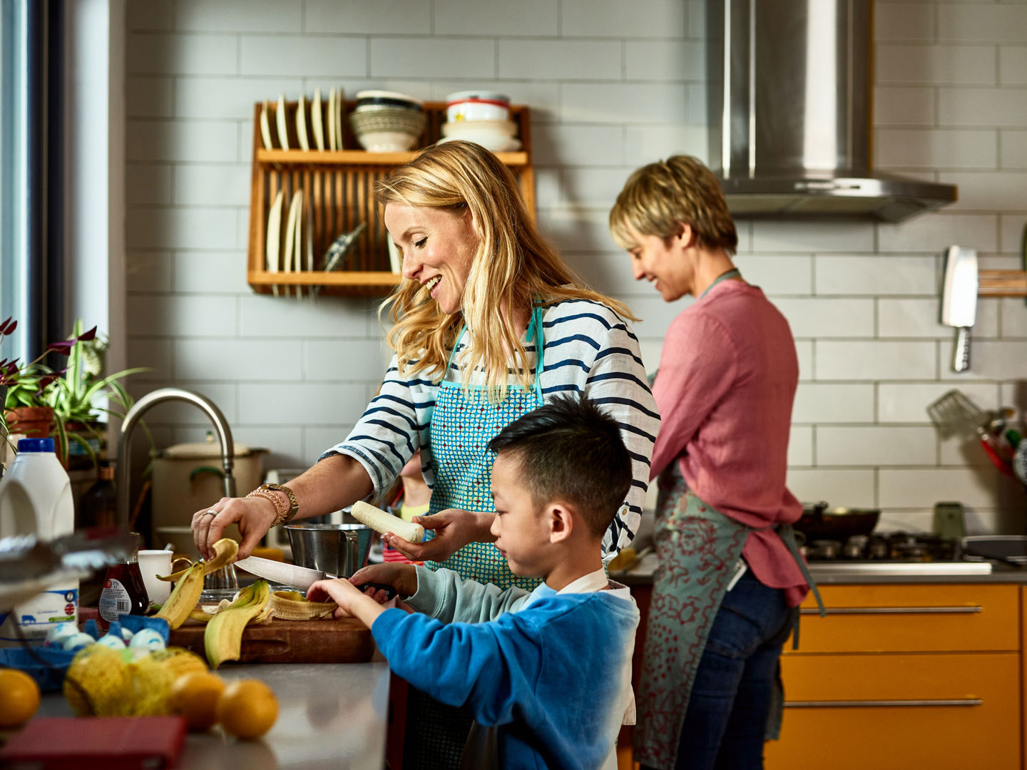 Two adults preparing food in the kitchen with a child
